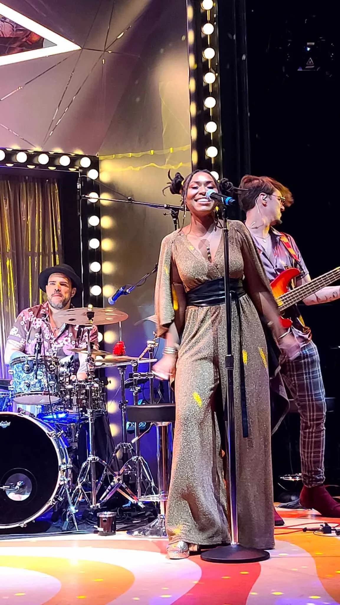 A singer and live band performing on stage aboard a Virgin Voyages ship