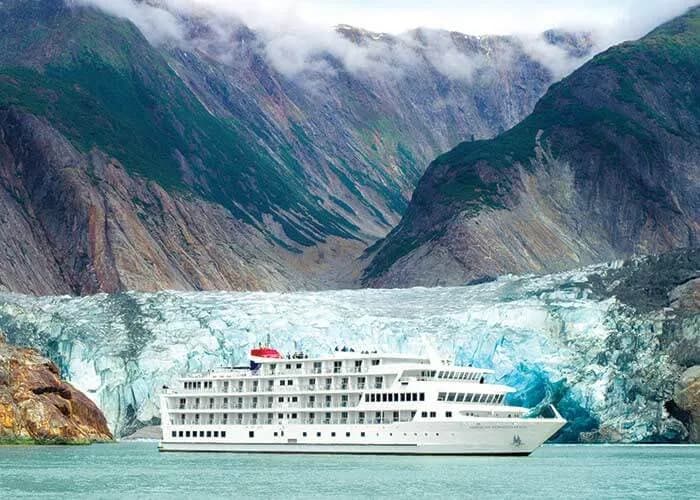 Small cruise ship dwarfed by a tidewater glacier in Alaska