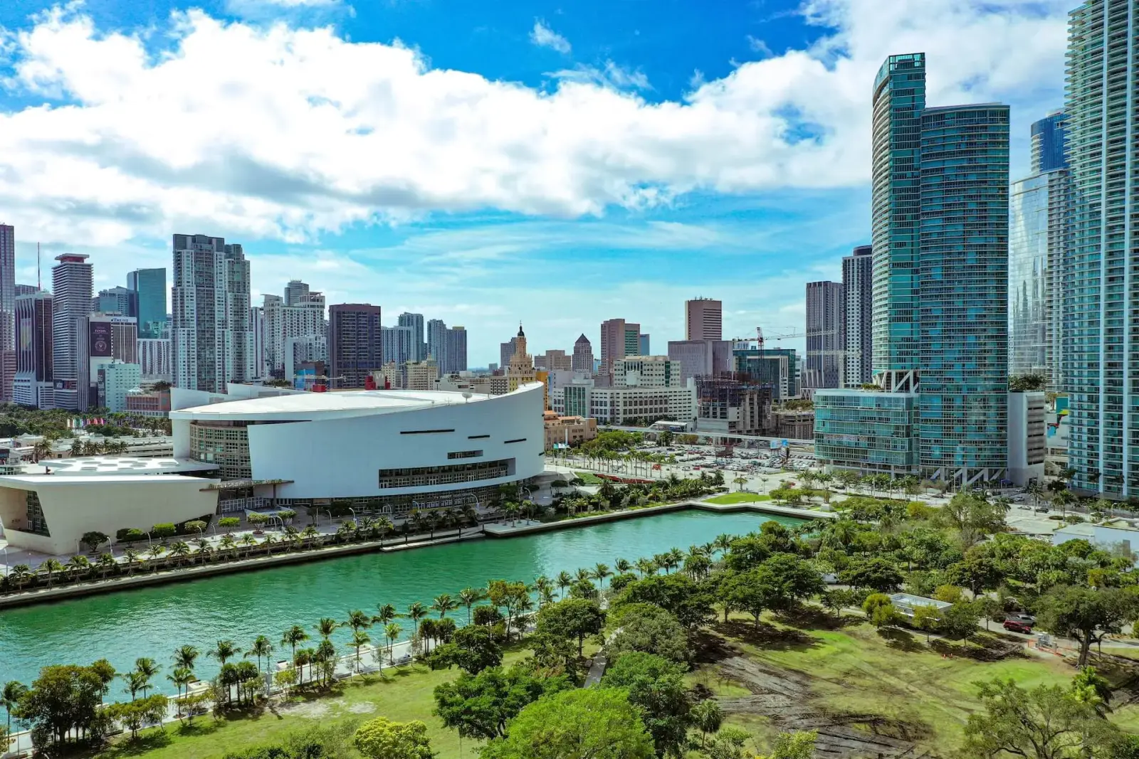 Downtown Miami skyline with waterfront park and palm-lined canal