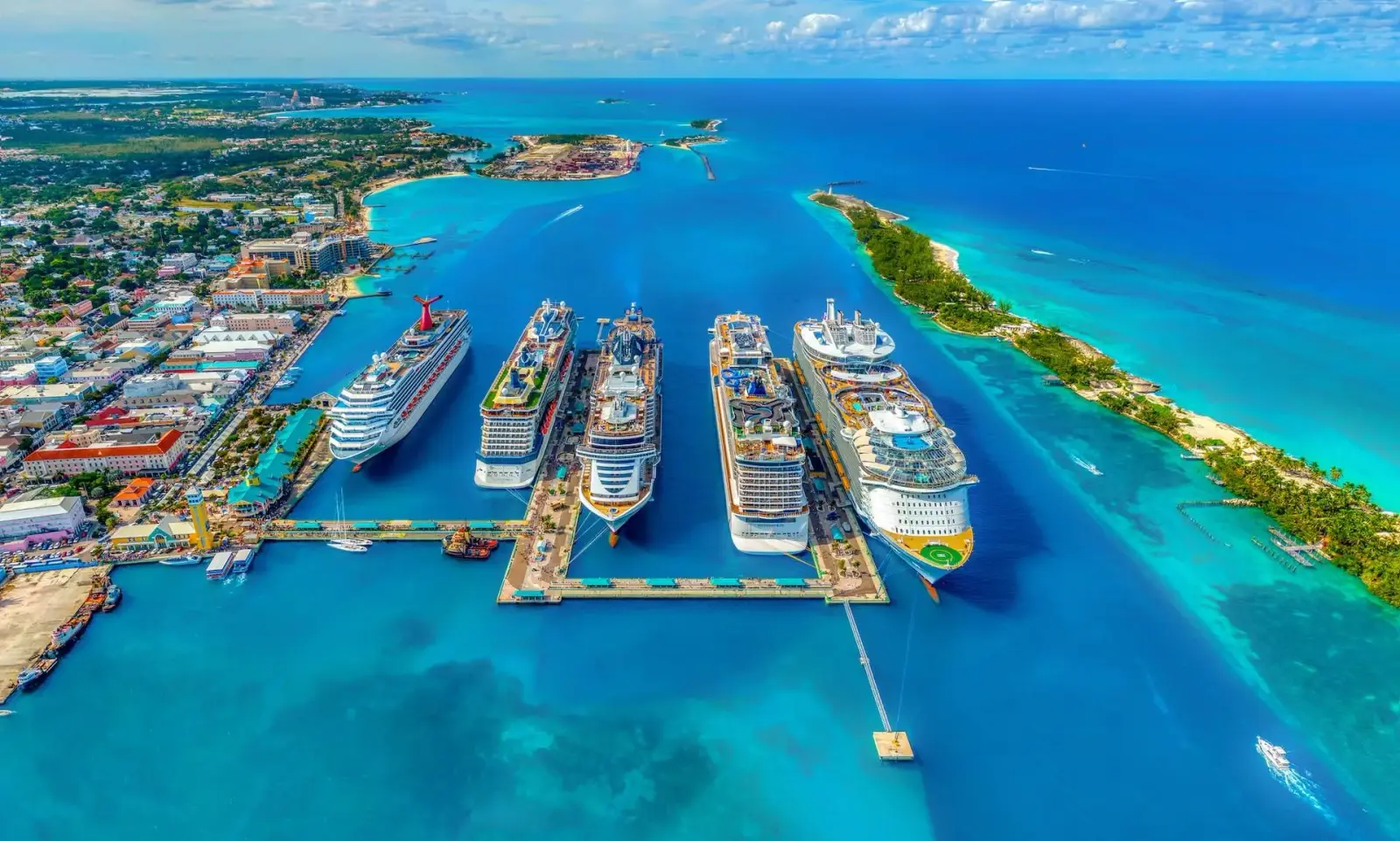 Aerial view of five cruise ships docked at a turquoise Bahamas port