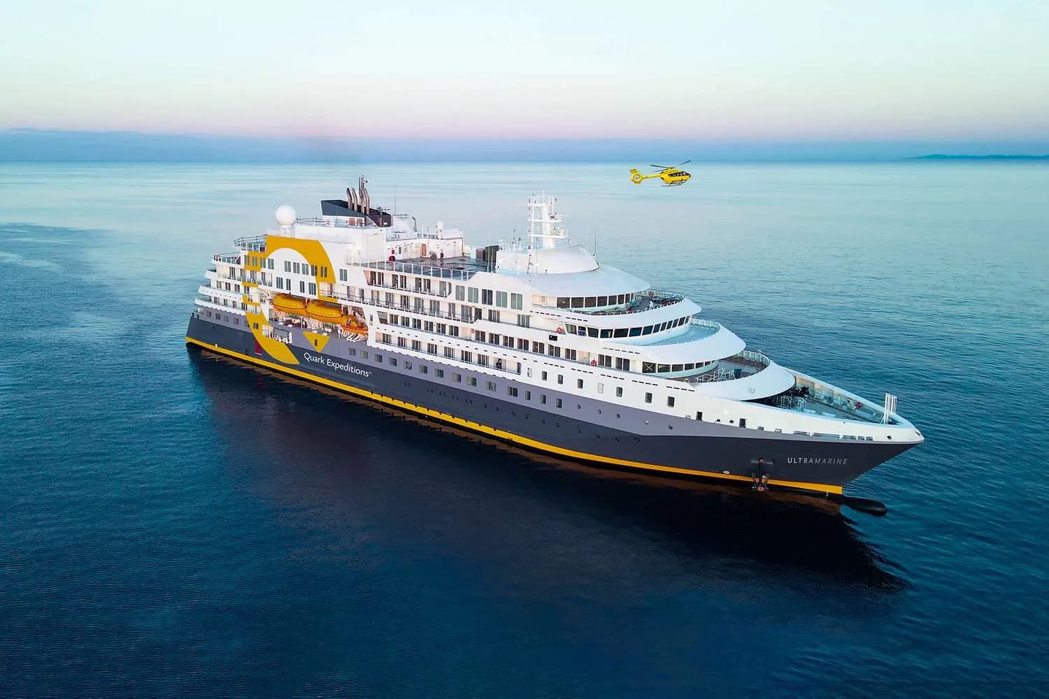 Quark Expeditions polar ship at sea with an expedition helicopter flying overhead