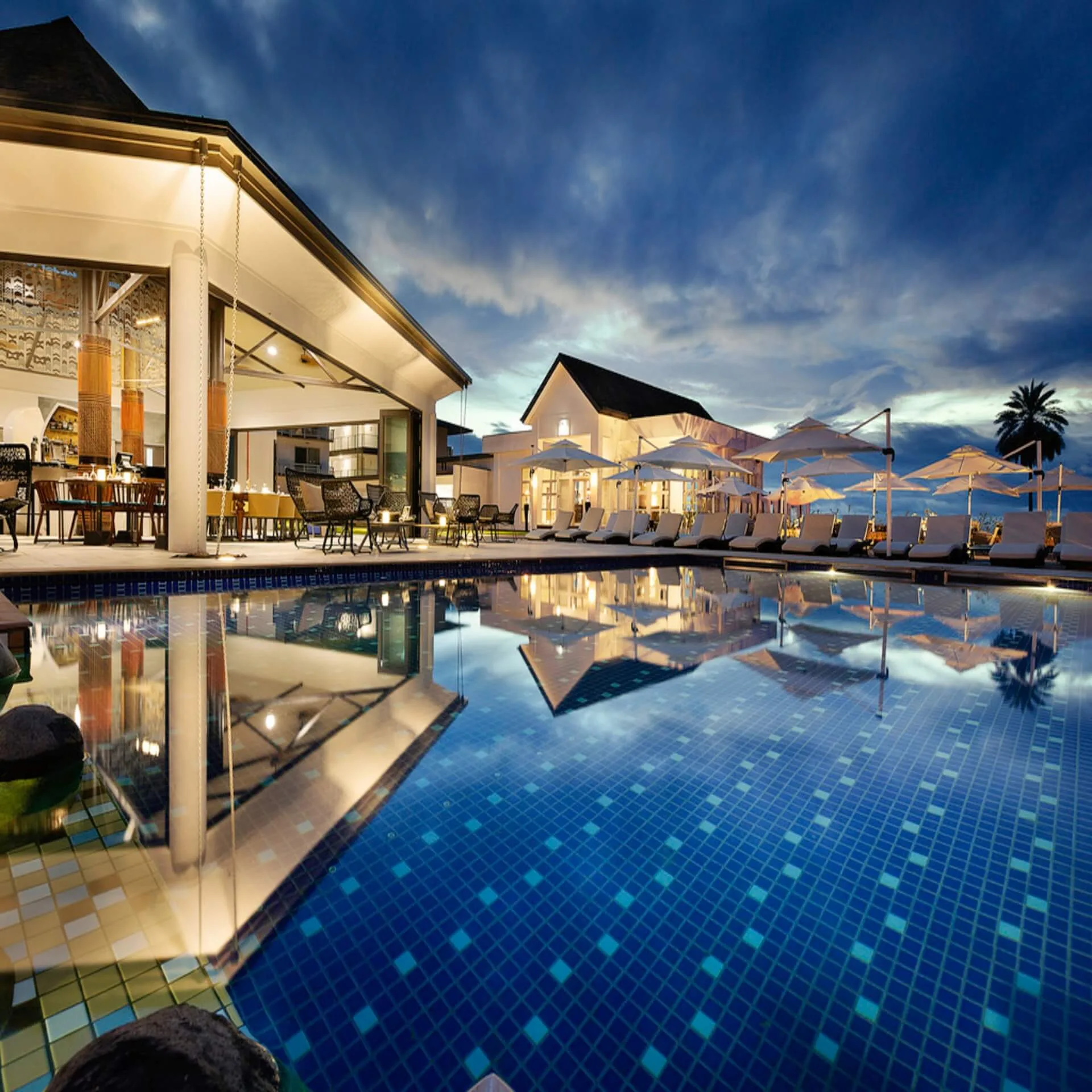 Quiet adults-only resort pool with loungers at the water's edge
