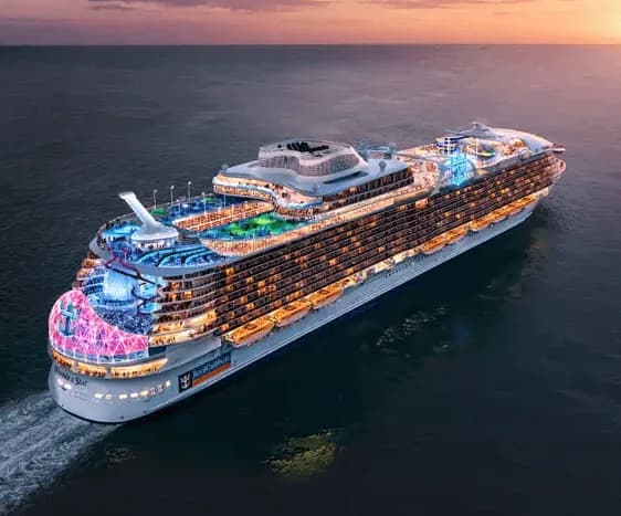 Royal Caribbean cruise ship at sea at dusk with its decks lit up