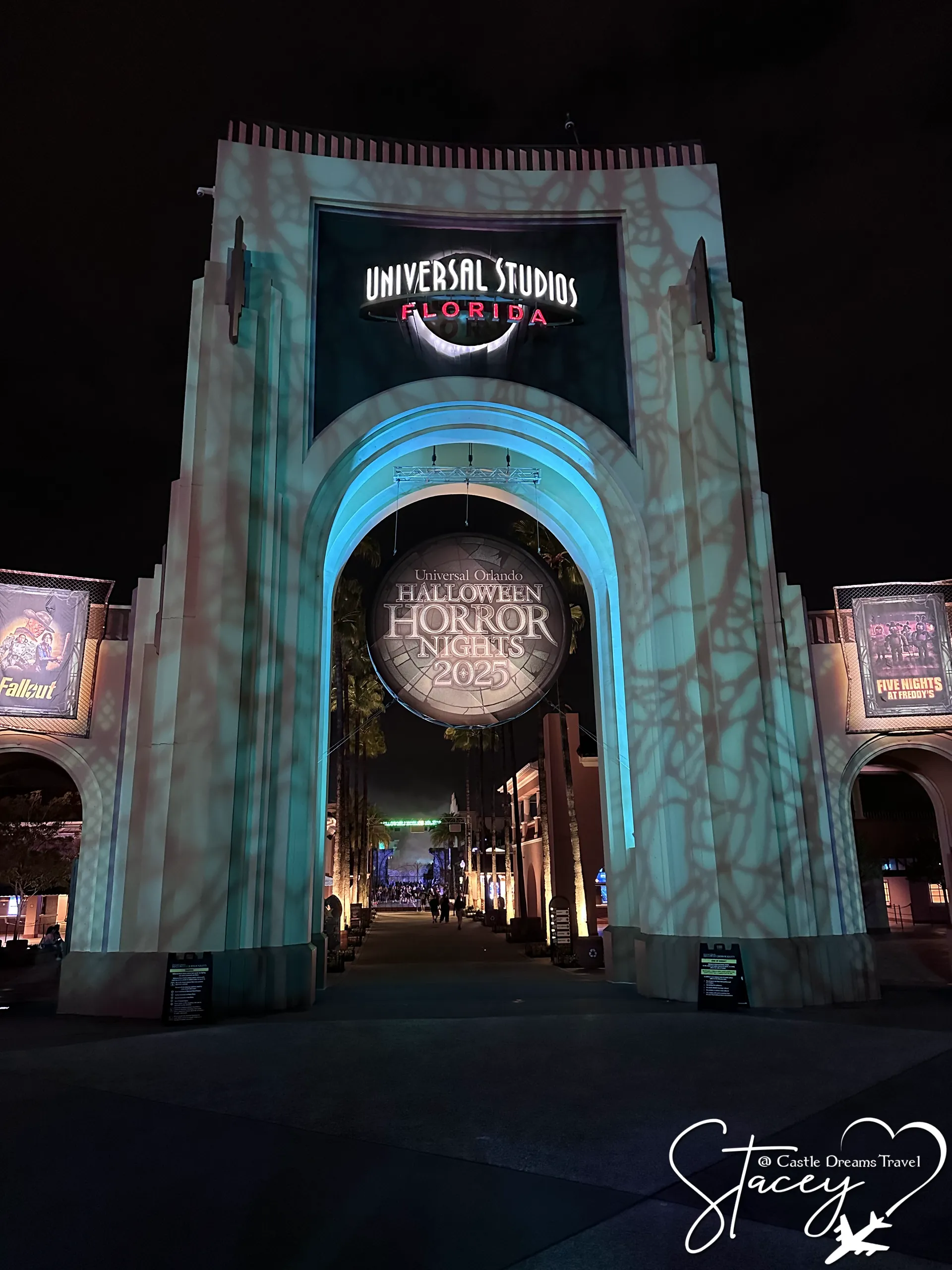 The Universal Studios Florida entrance arch at night, lit with a Halloween Horror Nights projection